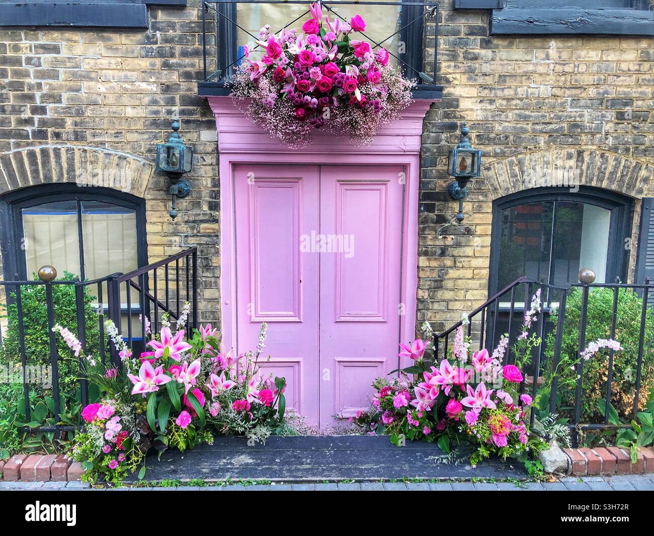 A pink wooden door and bouquets of flowers. - Smartphone Captured Stock Image