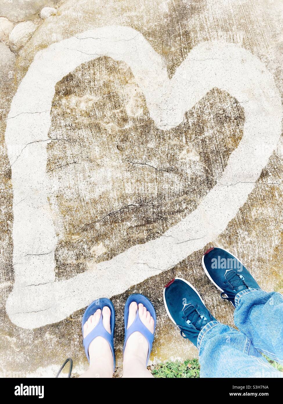 Man and woman’s feet together near a painted heart. Selfie of a couple in love. Valentines Day anniversary concept. - Smartphone Captured Stock Image
