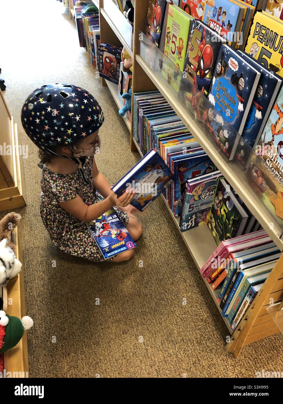 Female child looking at books in children’s section of a bookstore, USA. - Smartphone Captured Stock Image