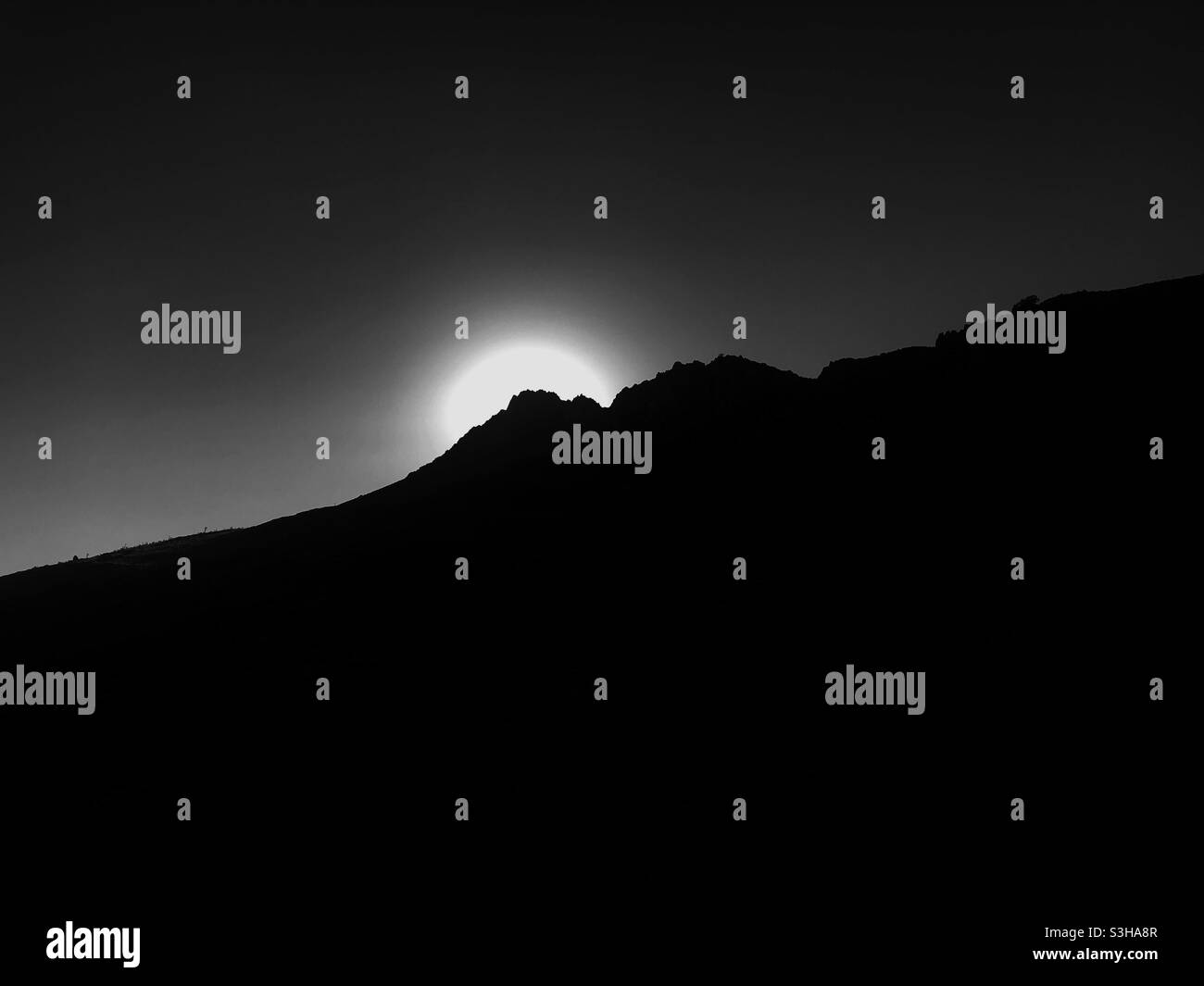 Monochrome image of The sun is rising behind mountains - Smartphone Captured Stock Image