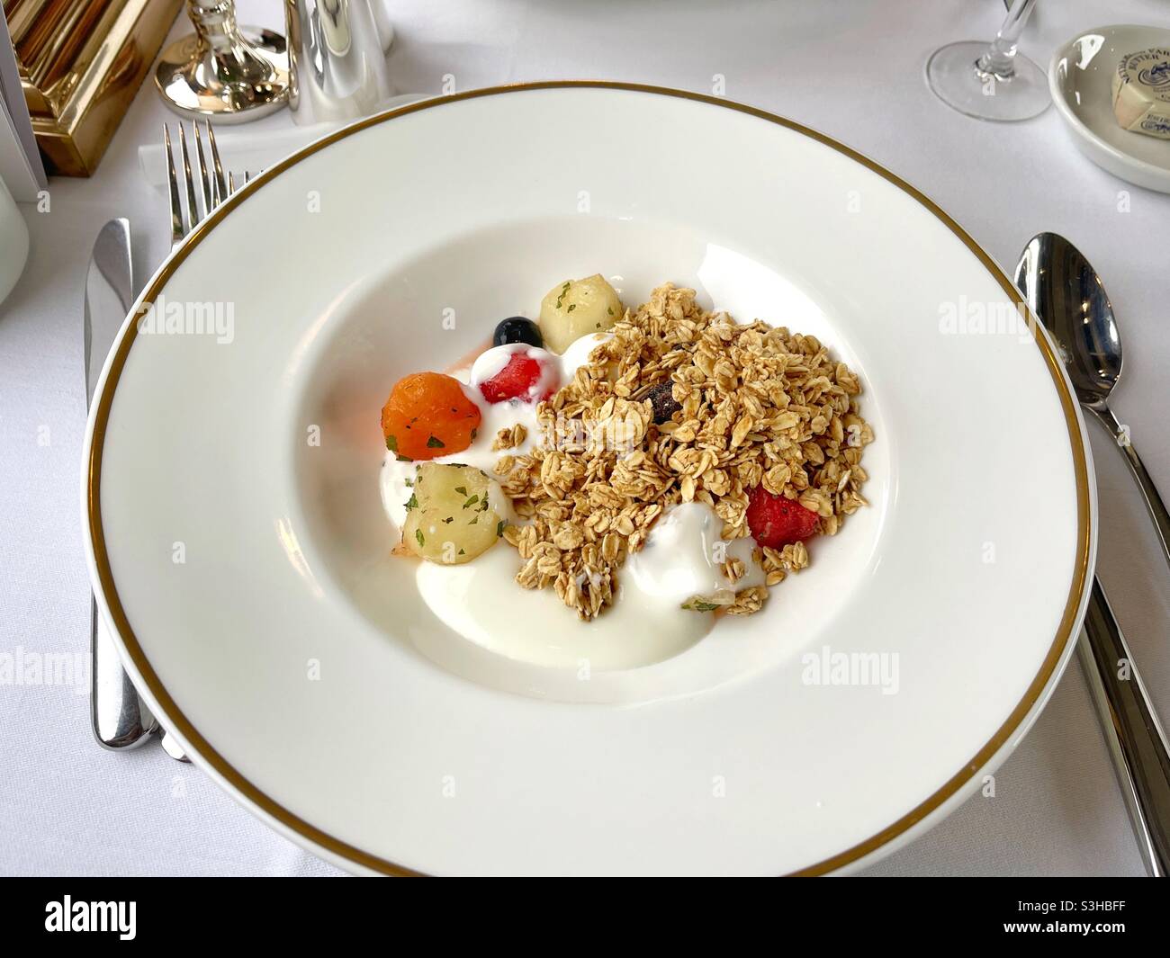 Trio of melon with oats and yoghurt in a large white dish on a table setting Stock Photo