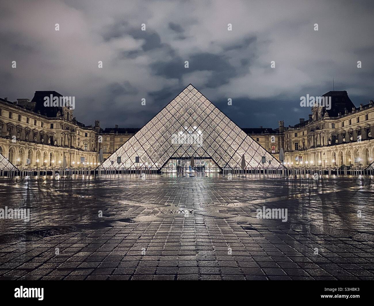 The courtyard of the Louvre Museum at night, with the iconic and controversial Pyramide du Louvre in the foreground. Paris, France Stock Photo