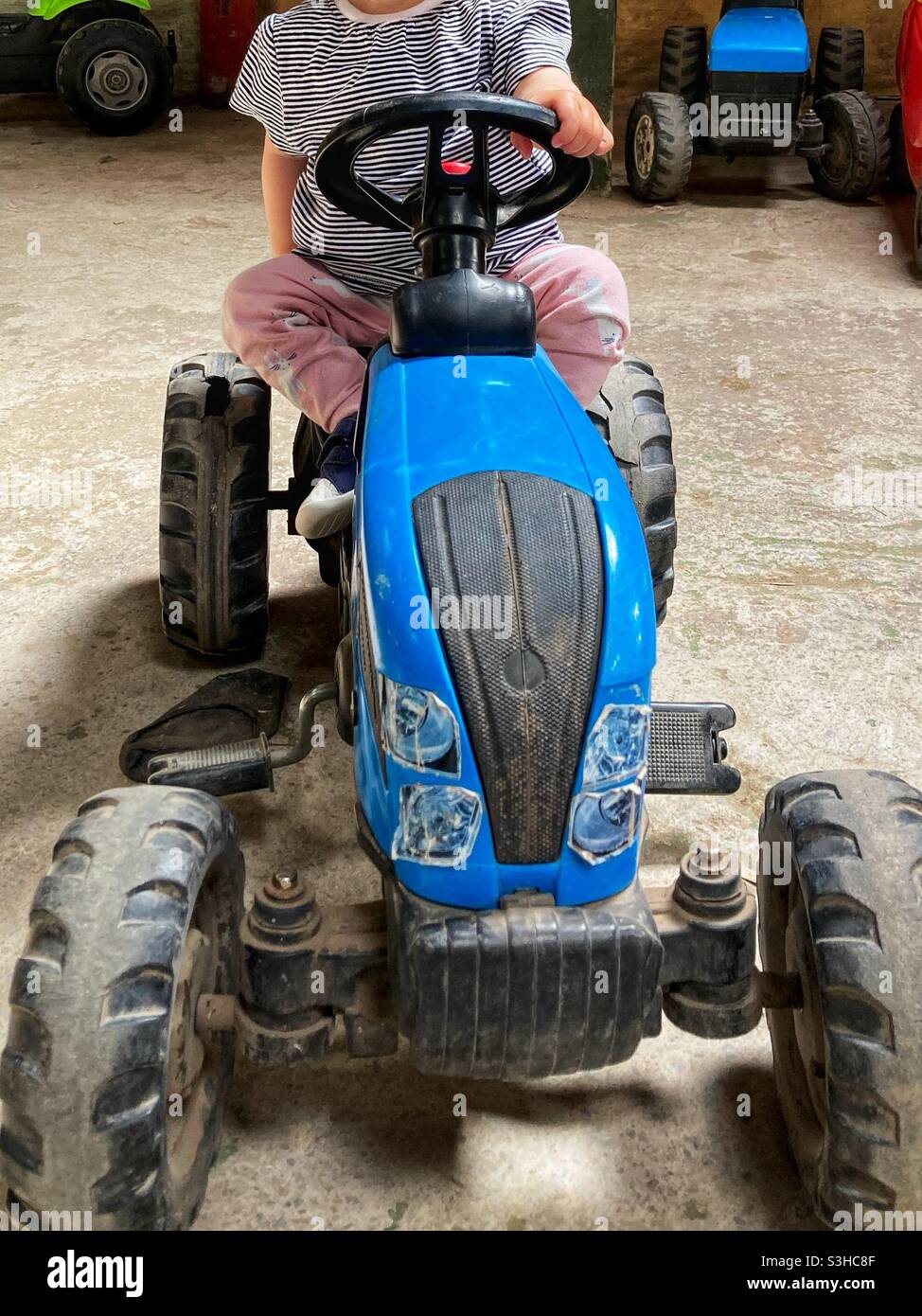 Child on toy tractor Stock Photo