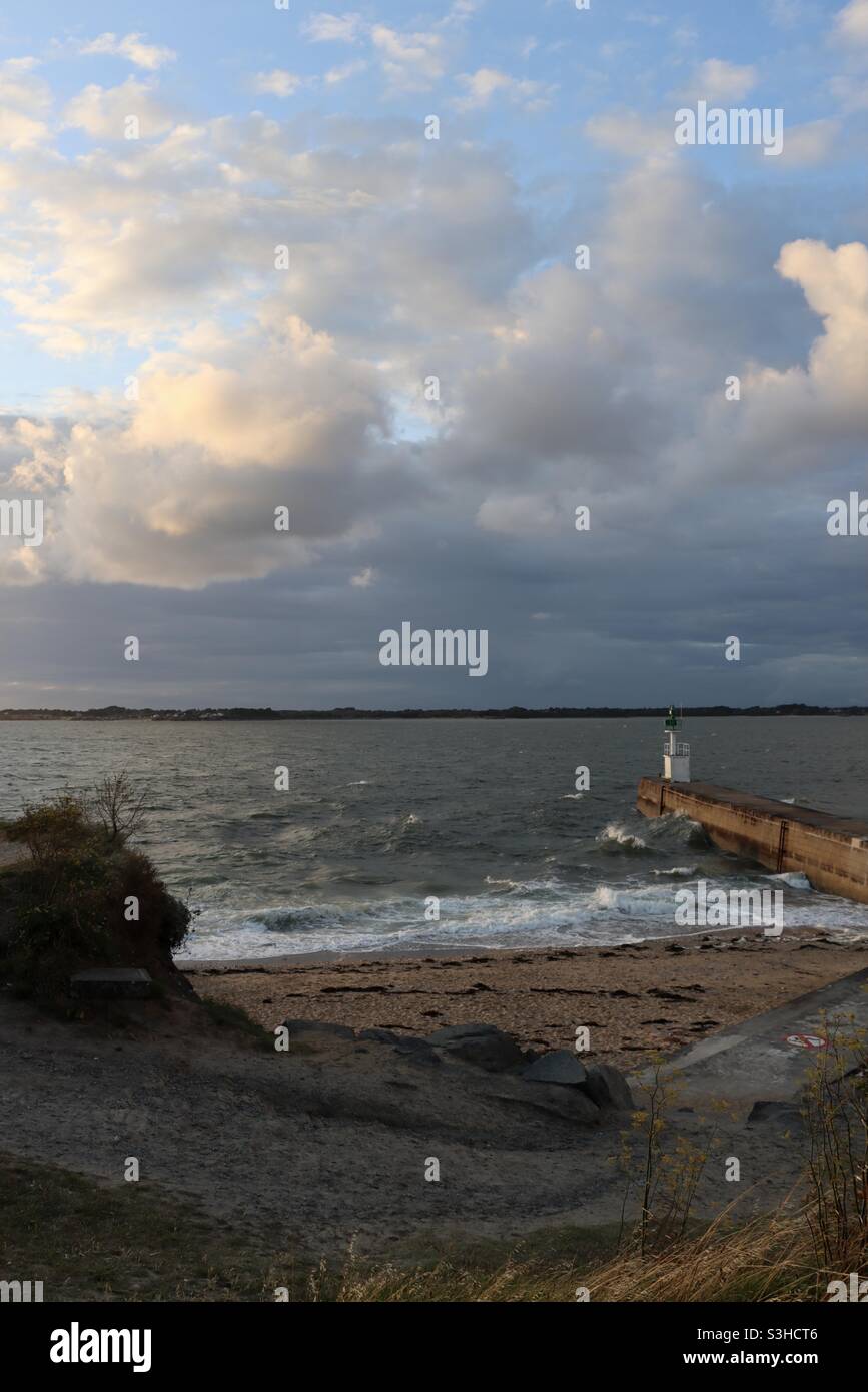Waves splashing on the pier at sunset time in Merquel, Loire Atlantique, France - Smartphone Captured Stock Image