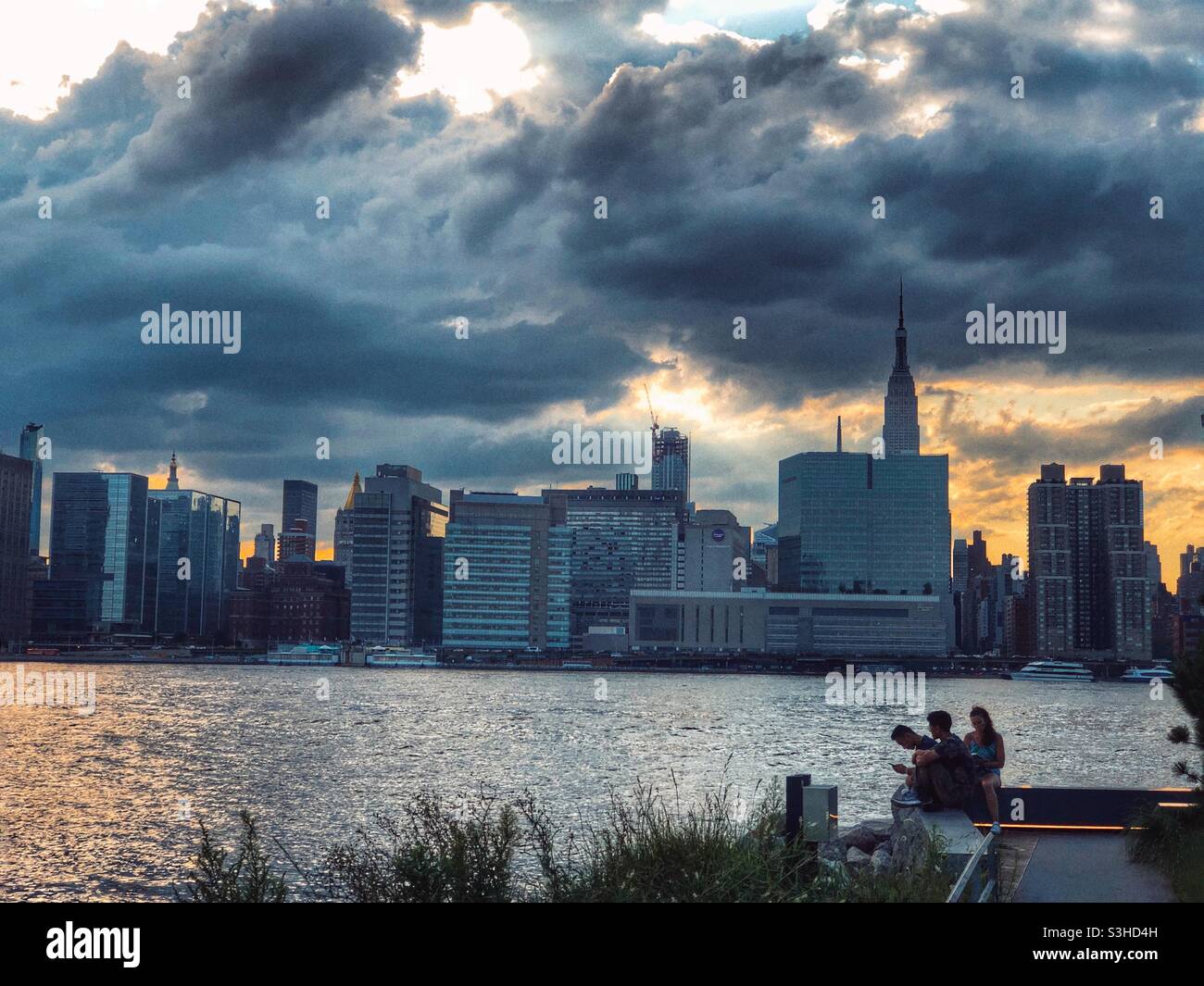 Young adults enjoying the magnificent view of Manhattan from Long Island City waterfront - Smartphone Captured Stock Image