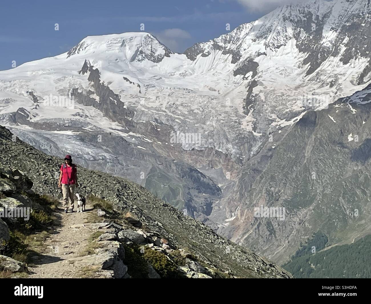 Hiker with dog on trail from Kreuzbodem to Almagelleralp. Valais Wallis,Saas Grund, Switzerland. Stock Photo