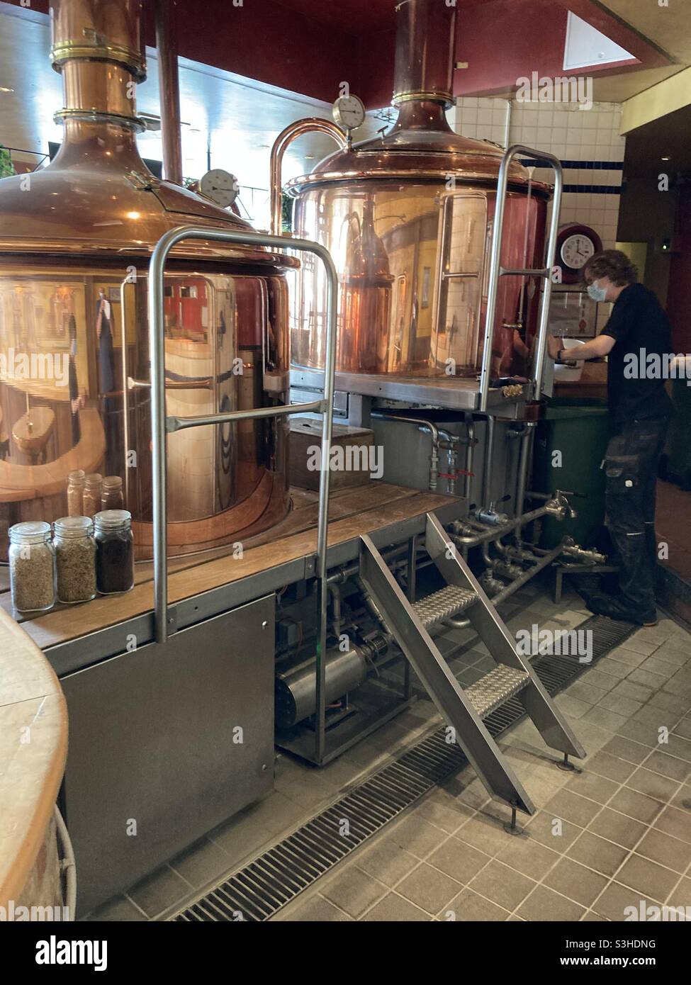 Restaurant employee adds ingredients to kettle brewing craft beer in a Hamburg gastronomy - Smartphone Captured Stock Image