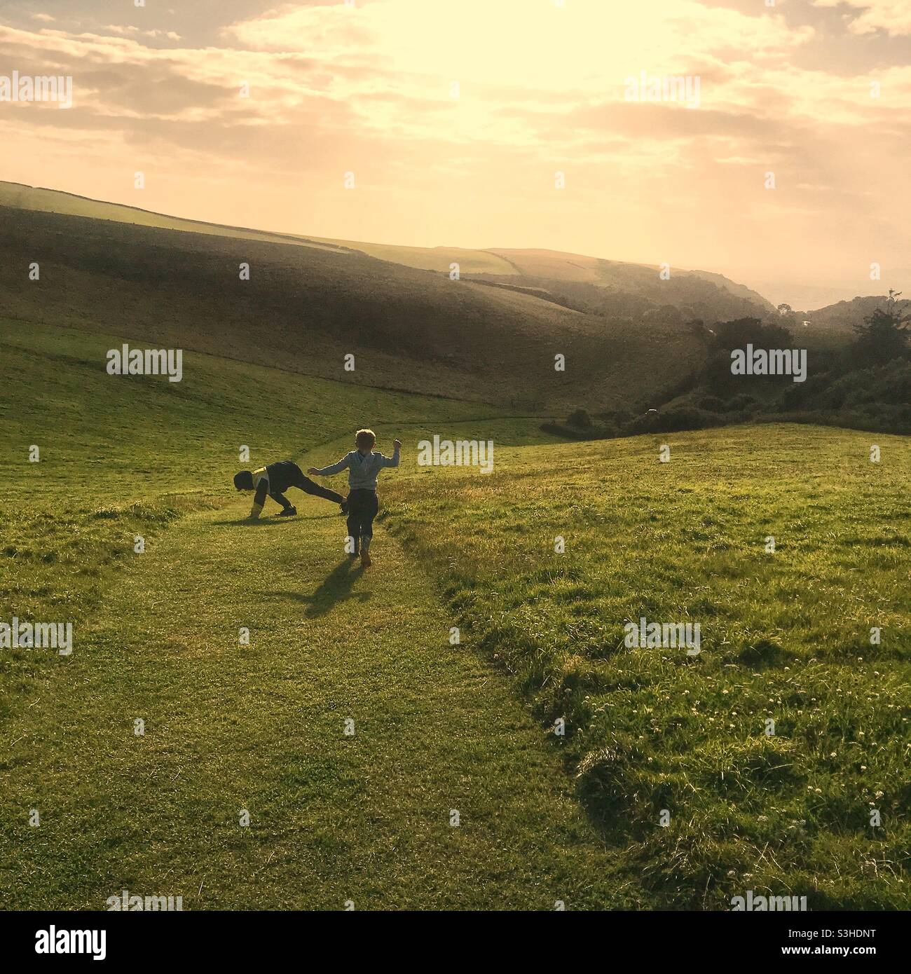 Boys running down a hill, Devon, England, United Kingdom Stock Photo