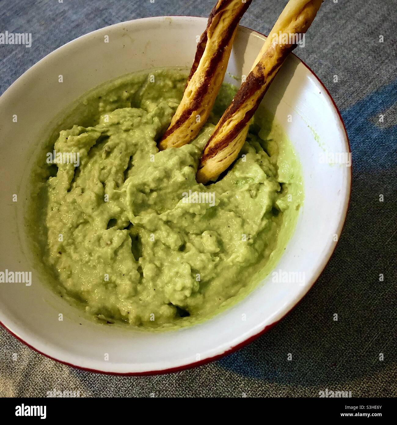 Homemade avocado dip in bowl with breadsticks. Stock Photo