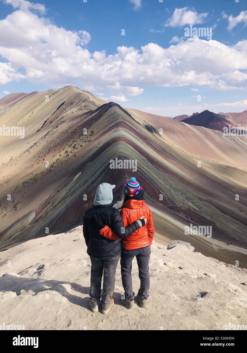 Women travelers celebrate reaching rainbow mountain in Peru Stock Photo