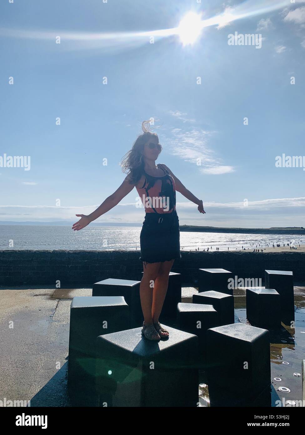 Woman standing on water feature at Barry island beach Wales - Smartphone Captured Stock Image