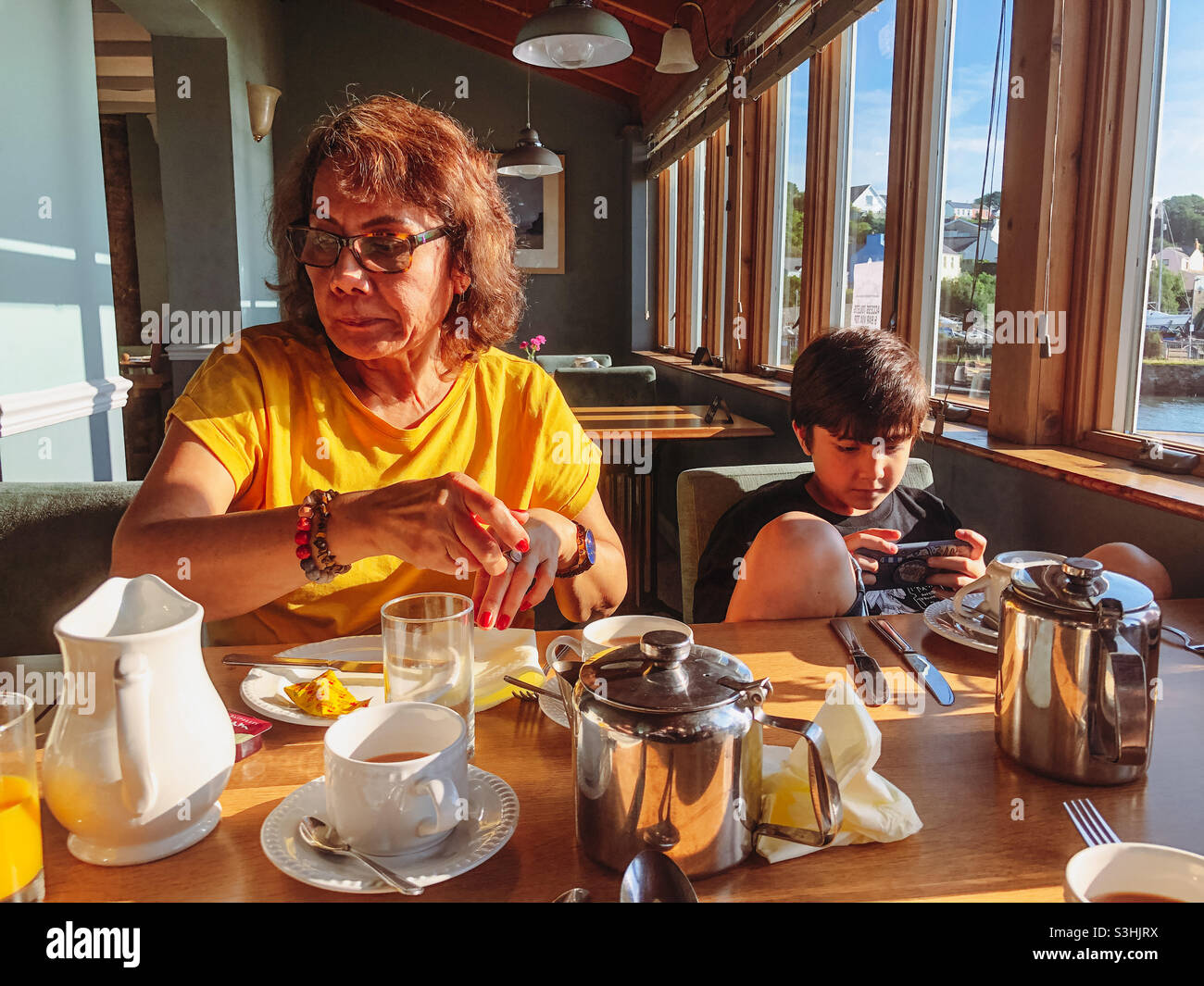 Boy abs his grandmother sat together at the breakfast table in a hotel. - Smartphone Captured Stock Image
