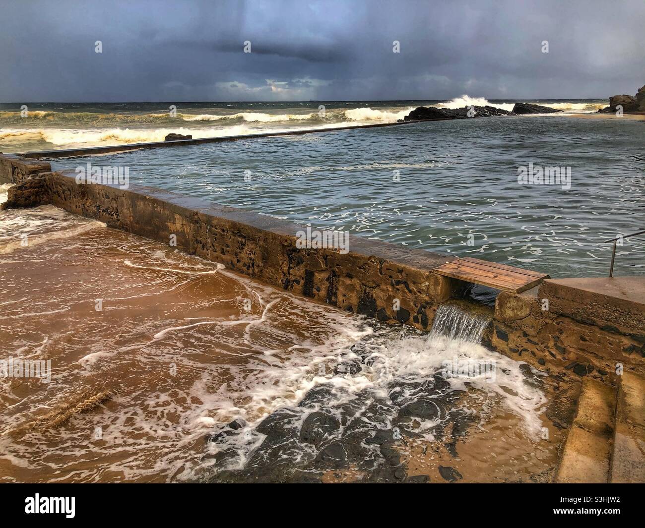 Moody sky and storm clouds over tidal pool and Indian Ocean, South Africa - Smartphone Captured Stock Image