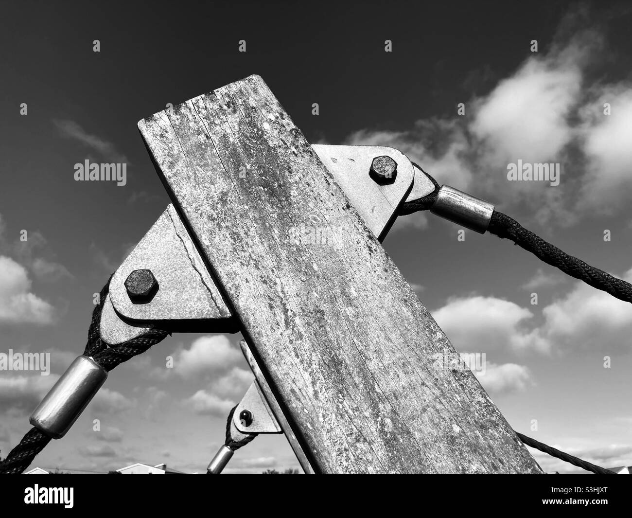 In front of the sky, ropes are attached to a gray weathered patterned beam with metal eyelets and bolts - Smartphone Captured Stock Image