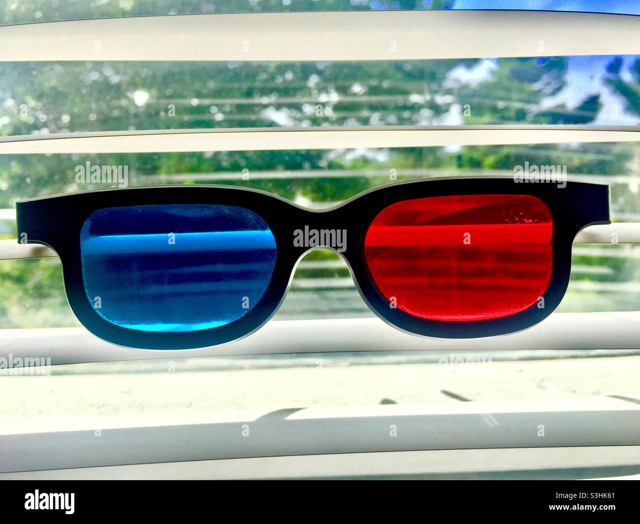 3D glasses on a window in front of Venetian blinds, Canada. Rose colour and blue, a surreal view. RGB. R and B in glasses, G outside. - Smartphone Captured Stock Image