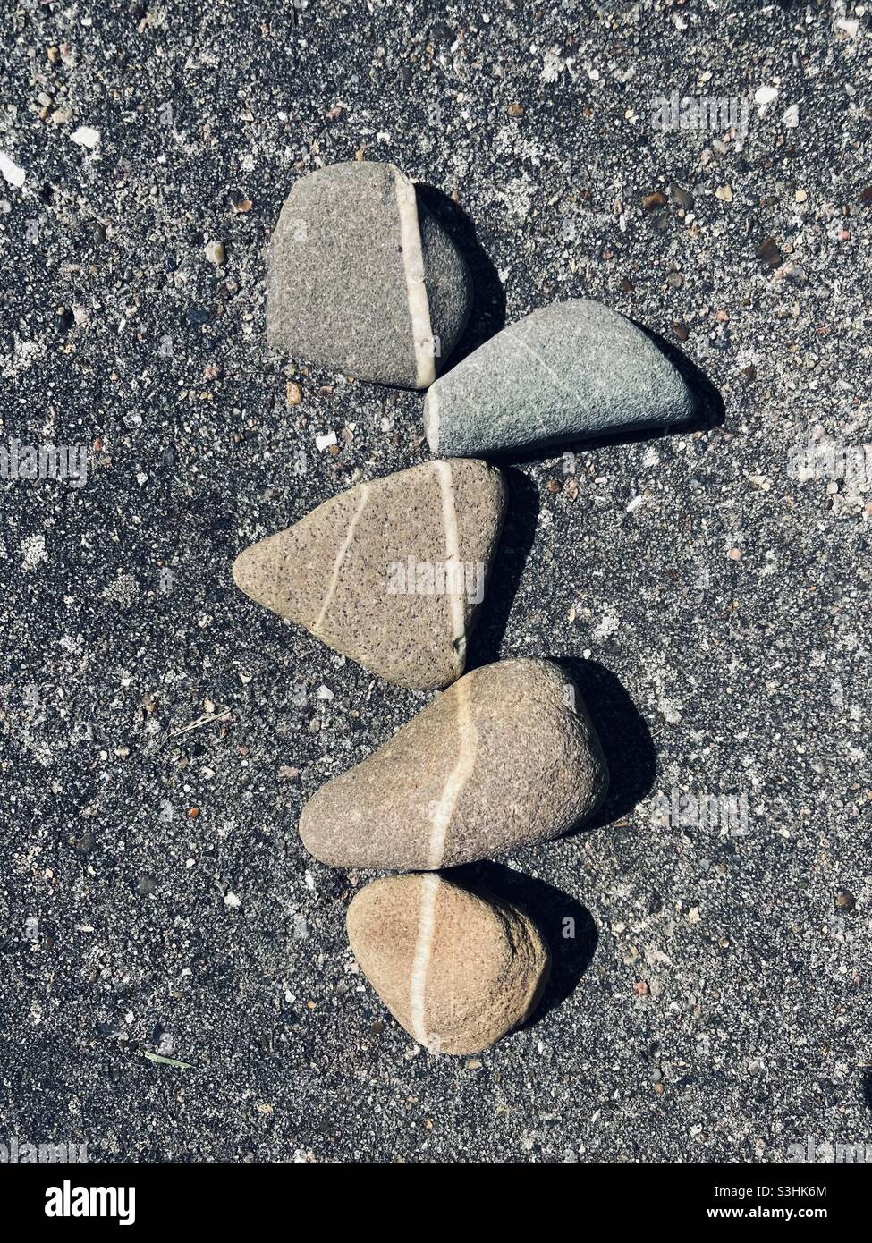 gray colored pebbles with a white stripe are so close together that the stripes form a continuous line - Smartphone Captured Stock Image