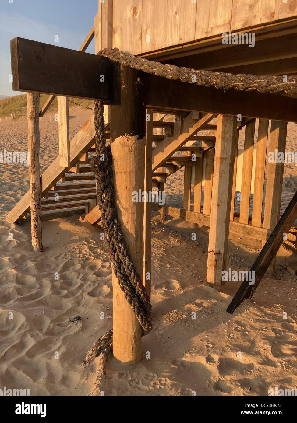 on the beach a strong rope is wrapped around the wooden pole of a beach house Stock Photo