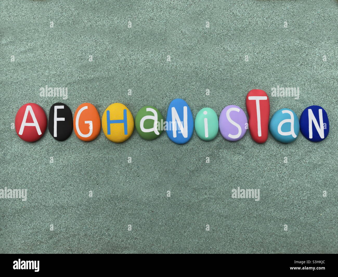 Afghanistan, Asian country, souvenir composed with hand painted multi colored stone letters over green sand - Smartphone Captured Stock Image