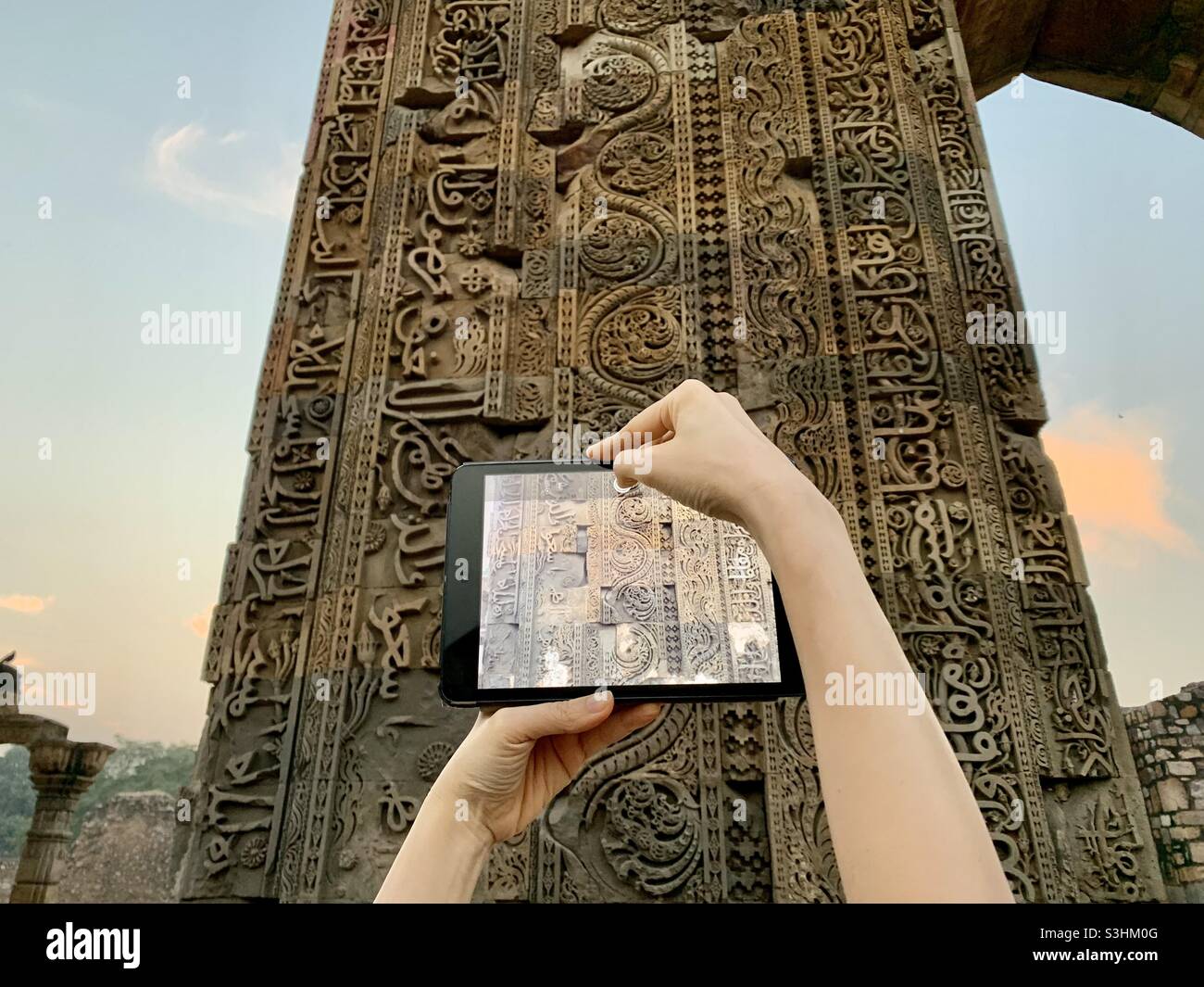 Old and new. iPad held in front of carvings at Qutab complex in New Delhi, India. Stock Photo