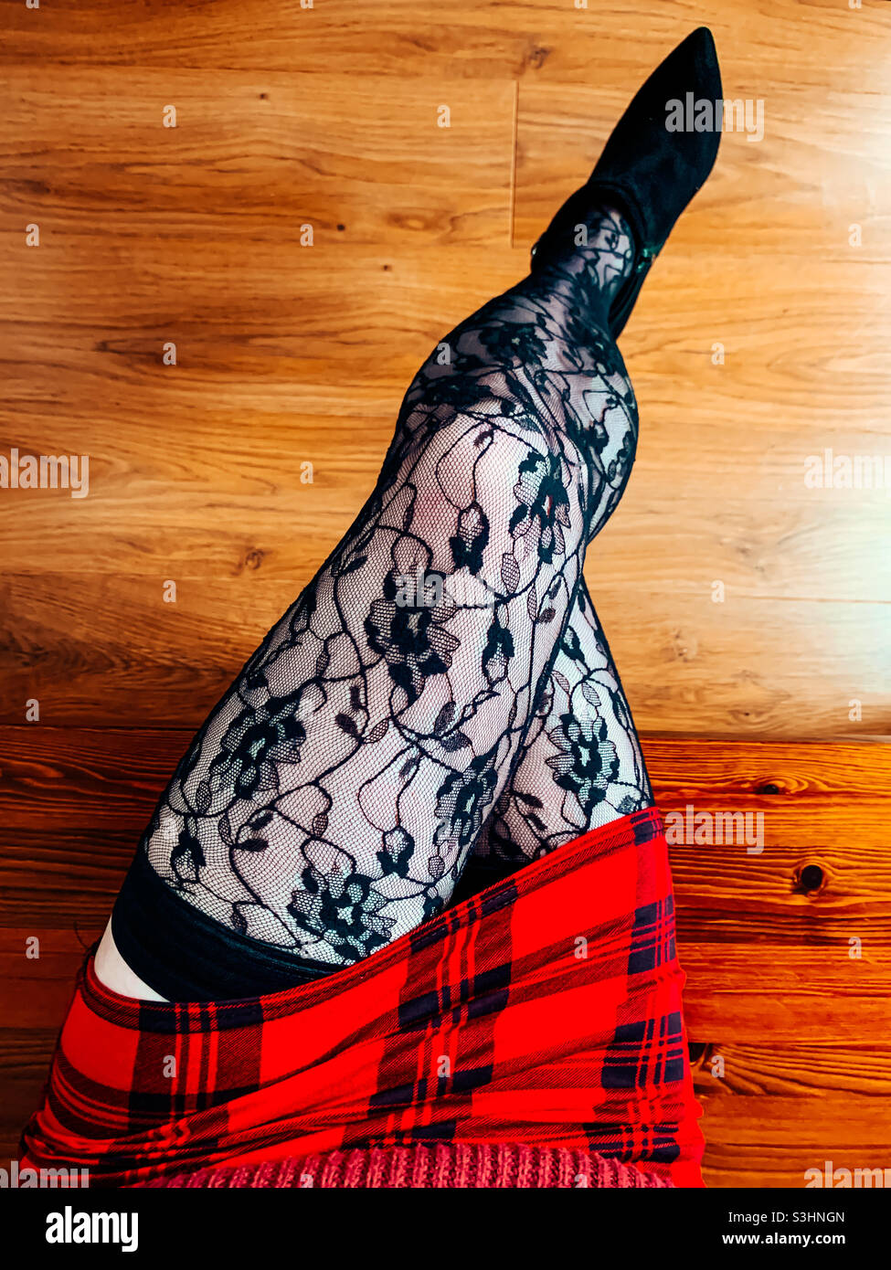 Top down view of a woman wearing a mini tartan skirt and patterned stockings - Smartphone Captured Stock Image