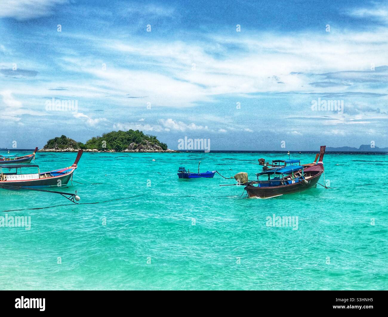 Long-tail boats anchored in the clear waters of Koh Lipe, Thailand Stock Photo