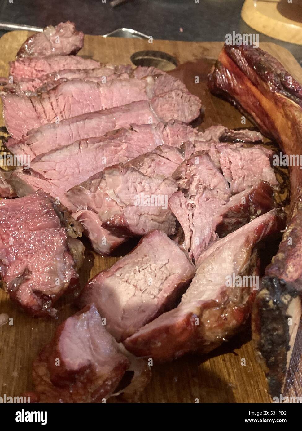 Sliced medium rare Tomahawk steak on a chopping board. Stock Photo
