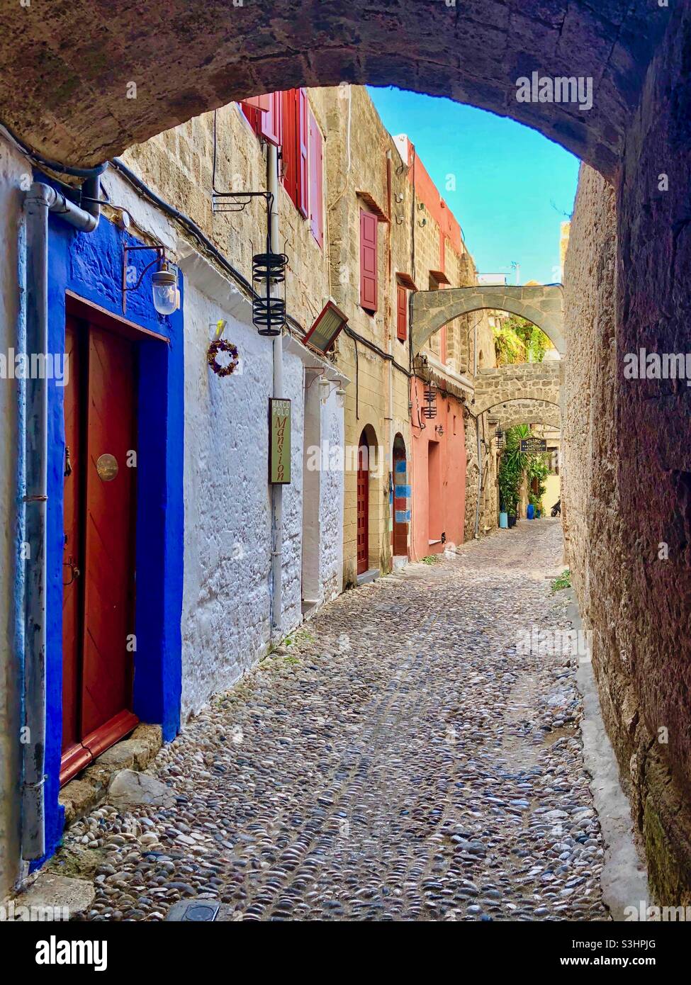 Walking through picturesque narrow street with colorful houses in Rhodes old town, Greece. - Smartphone Captured Stock Image