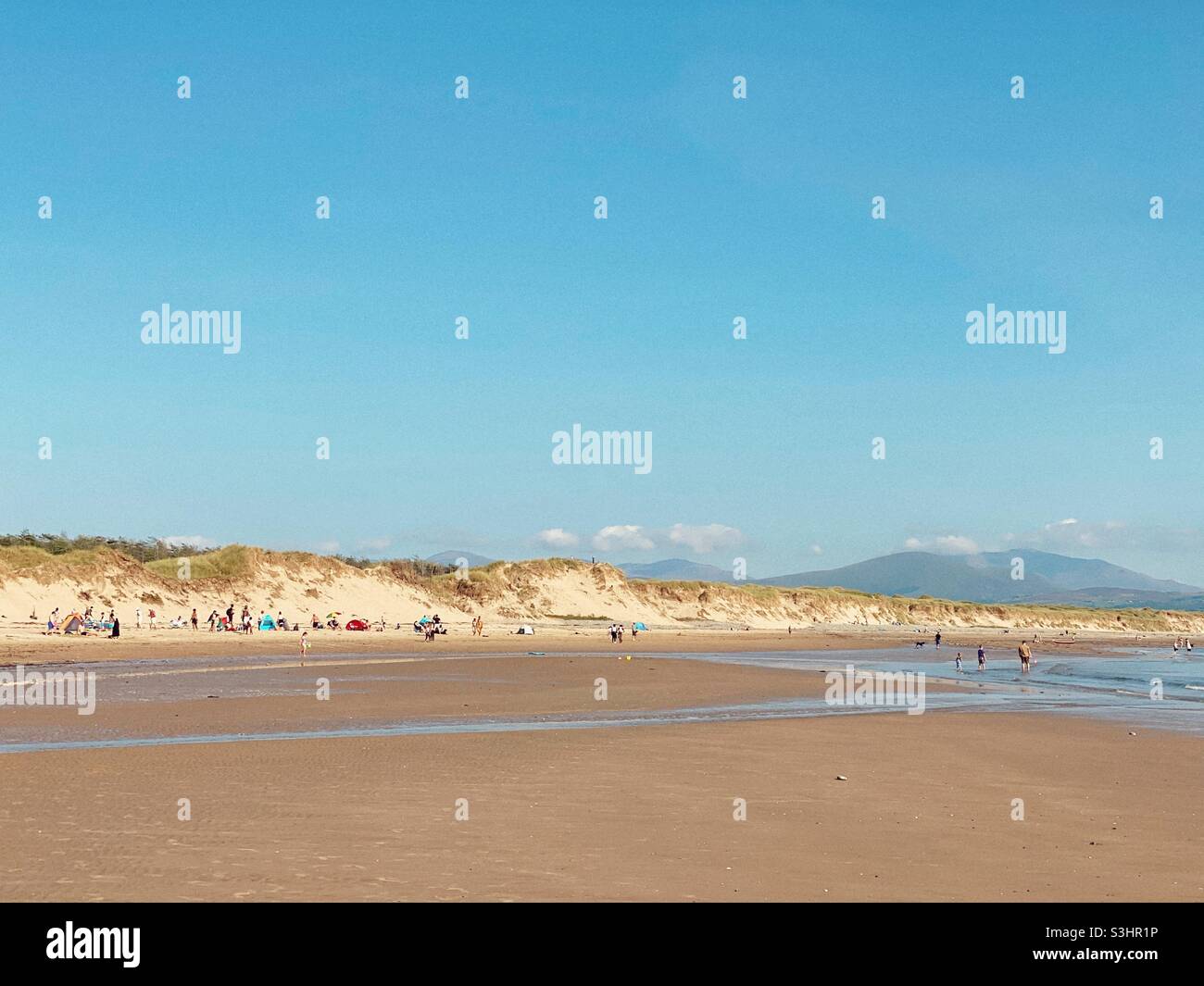 Newborough beach full of holidaymakers with view of the Snowdonia mountain range, Anglesey, north wales, uk, Gwynedd - Smartphone Captured Stock Image