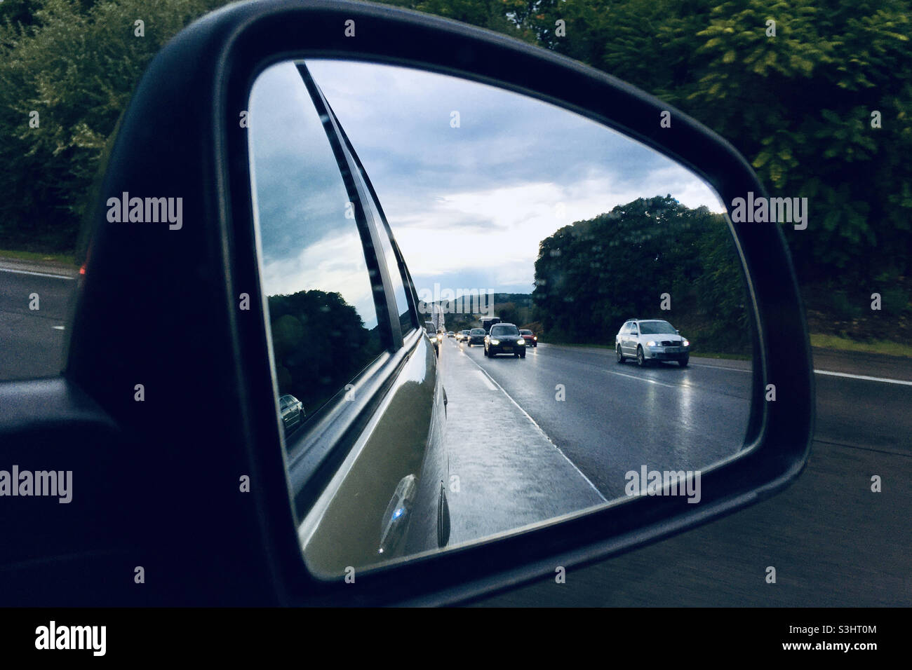 Heavy traffic in car mirror on M1 motorway in rainy weather, Hungary - Smartphone Captured Stock Image