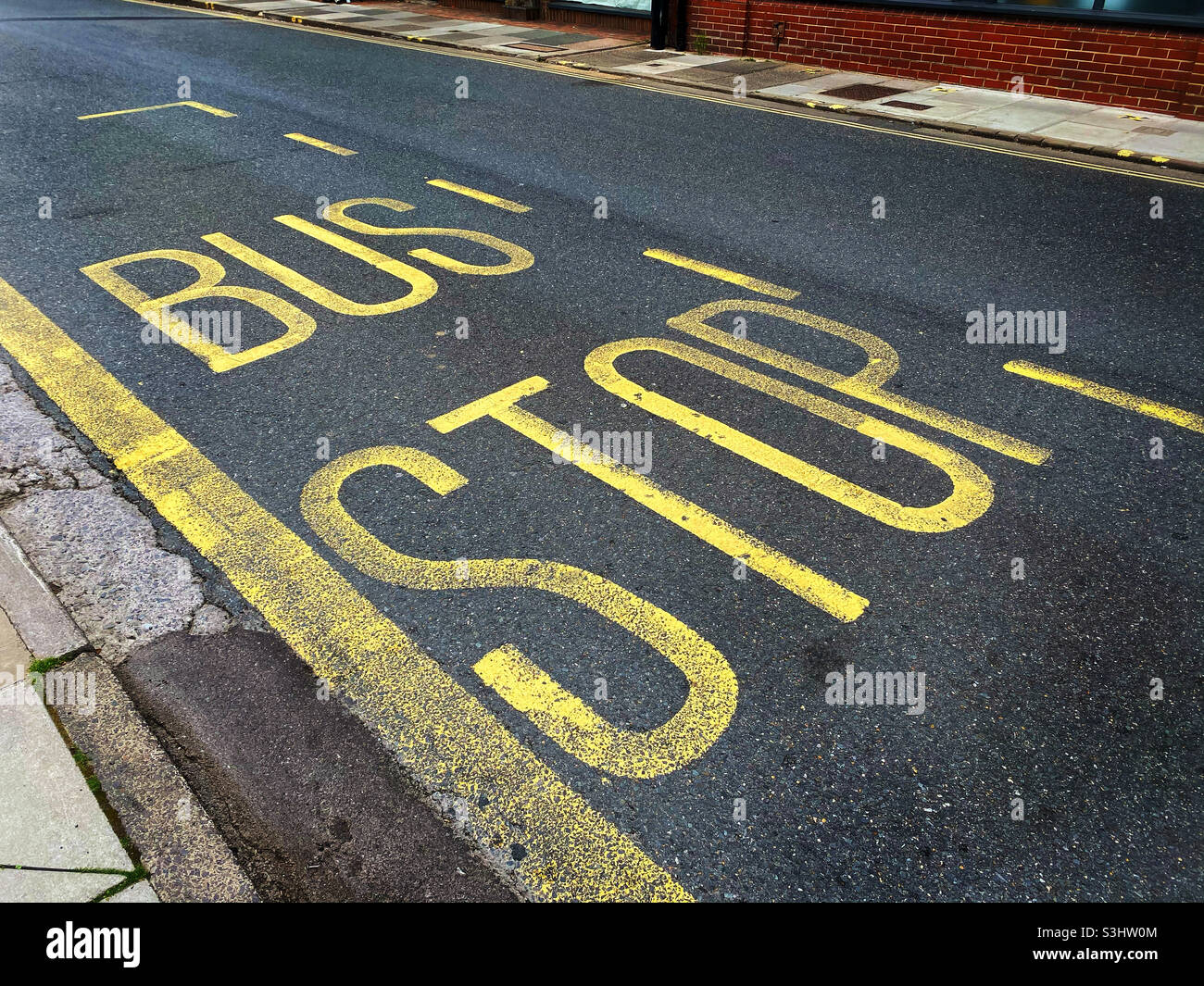 BUS STOP. Yellow information markings on a road in England, UK. Photo ©️ COLIN HOSKINS. - Smartphone Captured Stock Image