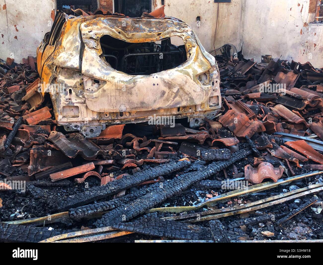 The aftermath of a house fire that started in the garage - the make of the car is indiscernible - Smartphone Captured Stock Image