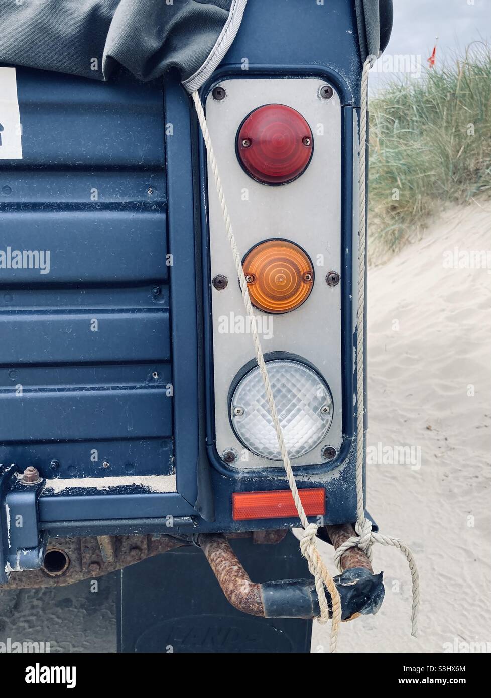 The vertical taillight bar of an old blue Land Rover on the beach - Smartphone Captured Stock Image