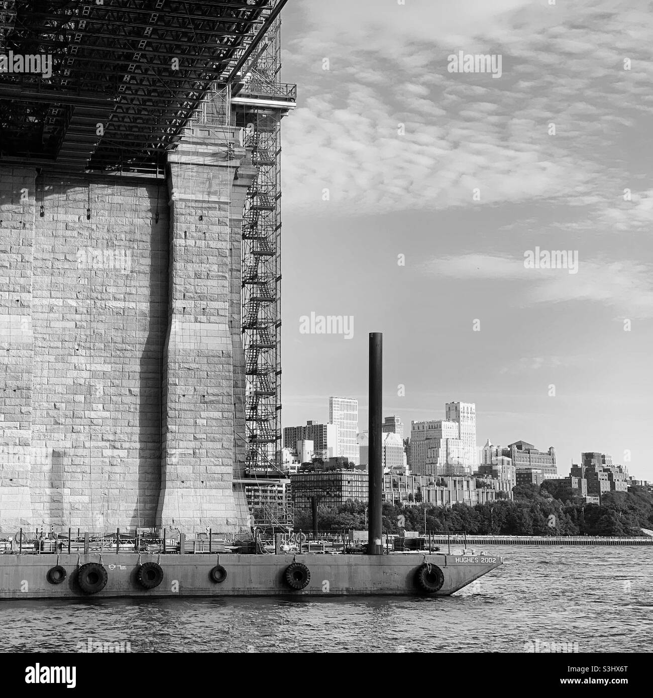 Black and white image of a barge on the East River, under Brooklyn Bridge, New York, New York, United States - Smartphone Captured Stock Image