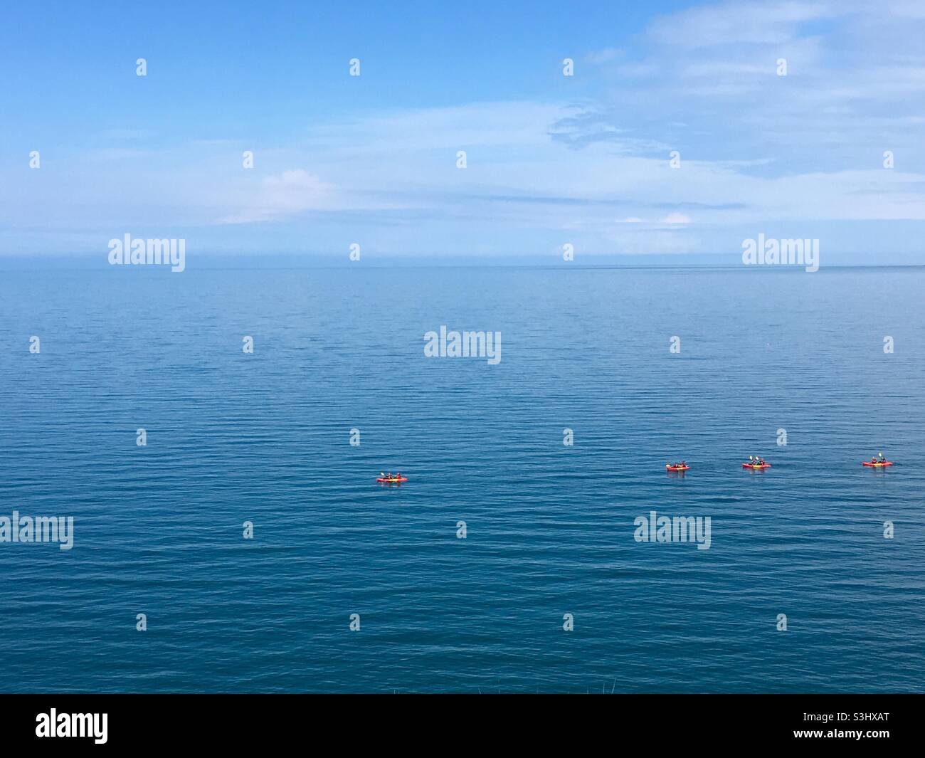 Four orange kayaks in the calm blue sea - Smartphone Captured Stock Image