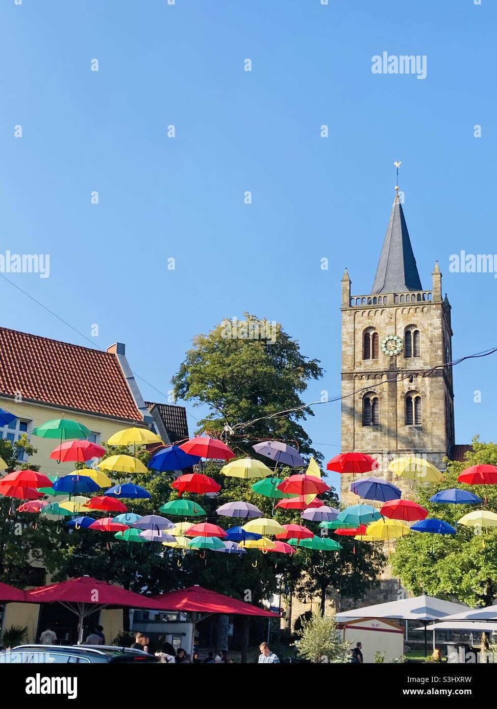 September 2021, in the German town of Ibbenbüren, many colorful umbrellas hang stretched across the market square in fine weather and blue skies. - Smartphone Captured Stock Image