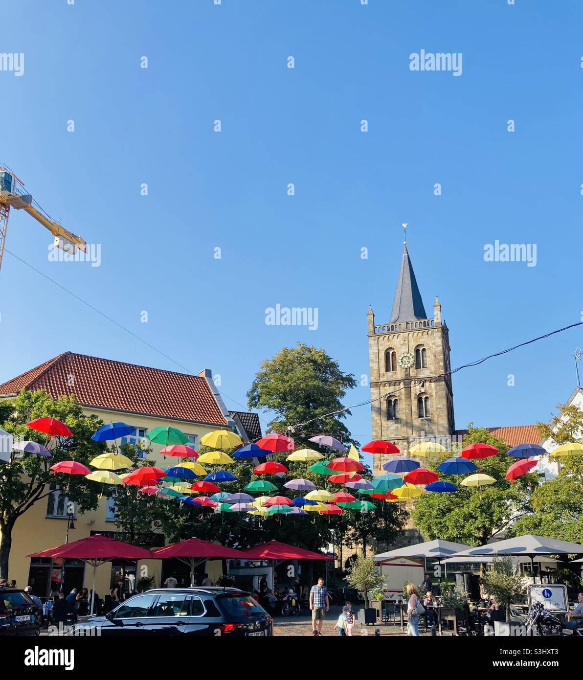 September 2021, in the German town of Ibbenbüren, many colorful umbrellas hang stretched across the market square in fine weather and blue skies. - Smartphone Captured Stock Image