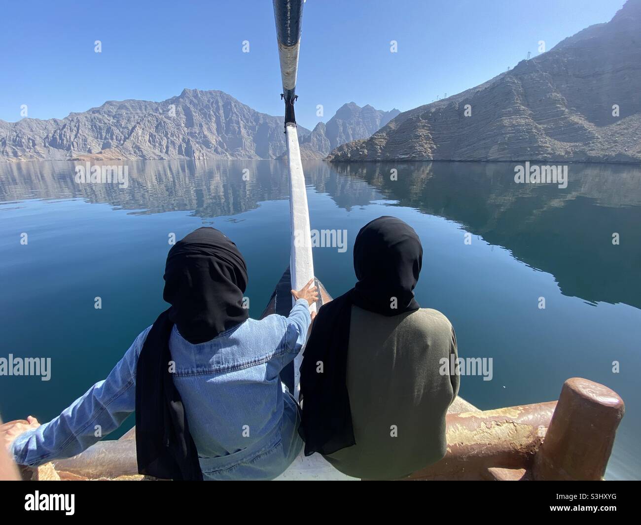 Front view: girls sitting at front of a ship,known as dhaw, watching the view and nature - Smartphone Captured Stock Image