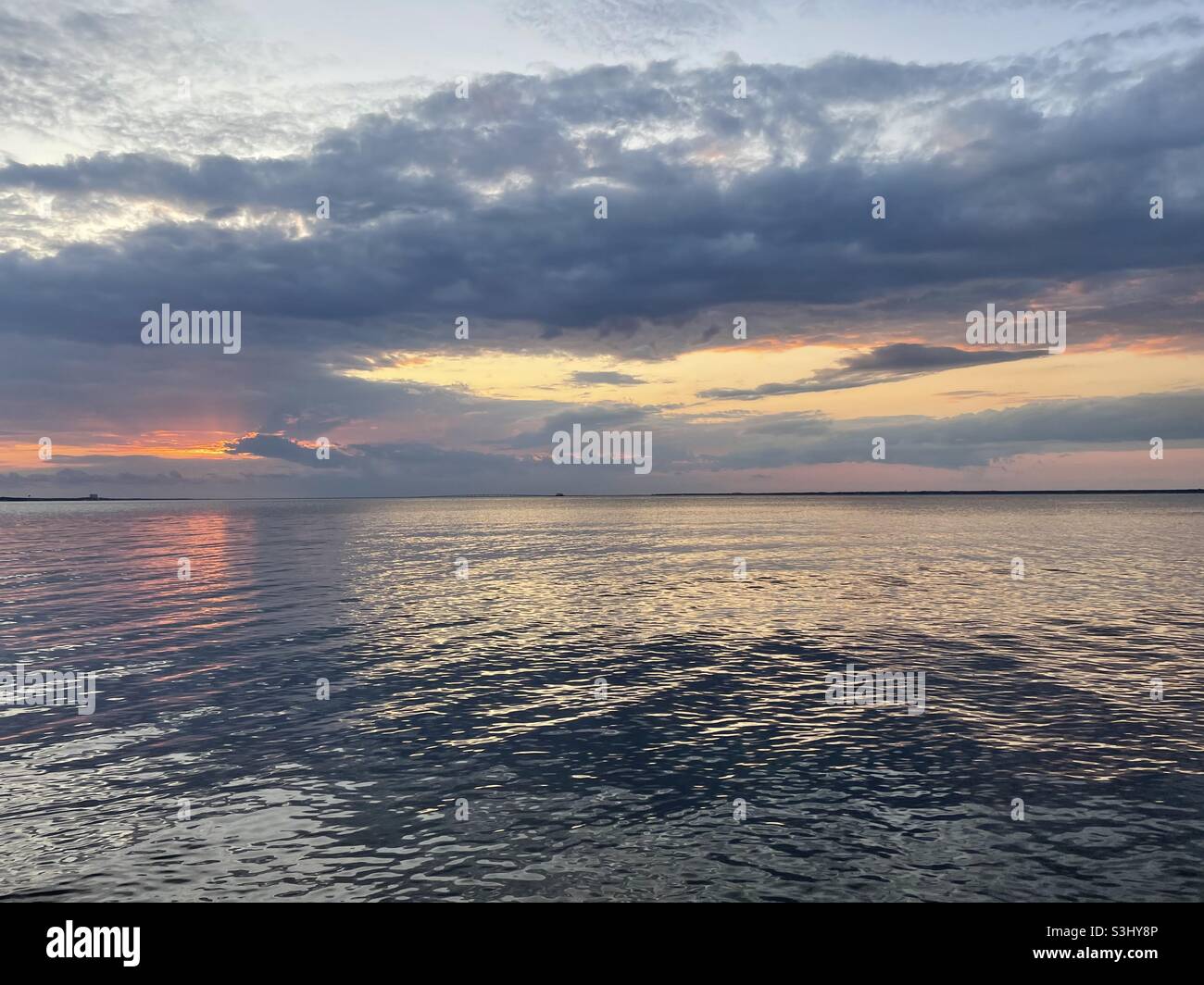 Colorful stormy sunset skies with reflections onto bay water Stock ...