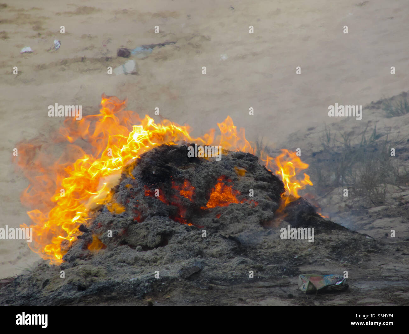 The pipe of garbage is being burned to ashes on the beach Stock Photo