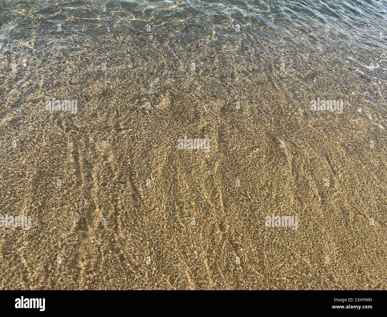 Beach water across a Sandy shore line clear ocean water Stock Photo - Alamy
