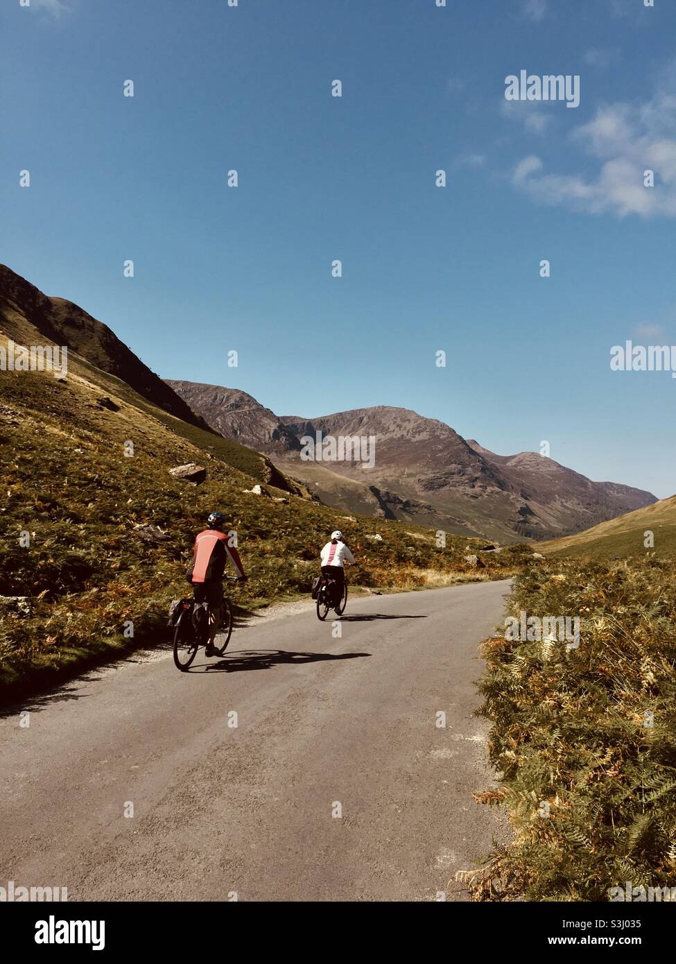 Cycling the winding narrow roads of the Lake District in Honister Pass Cumbria - cyclists cycling staycation summer activity holiday Stock Photo