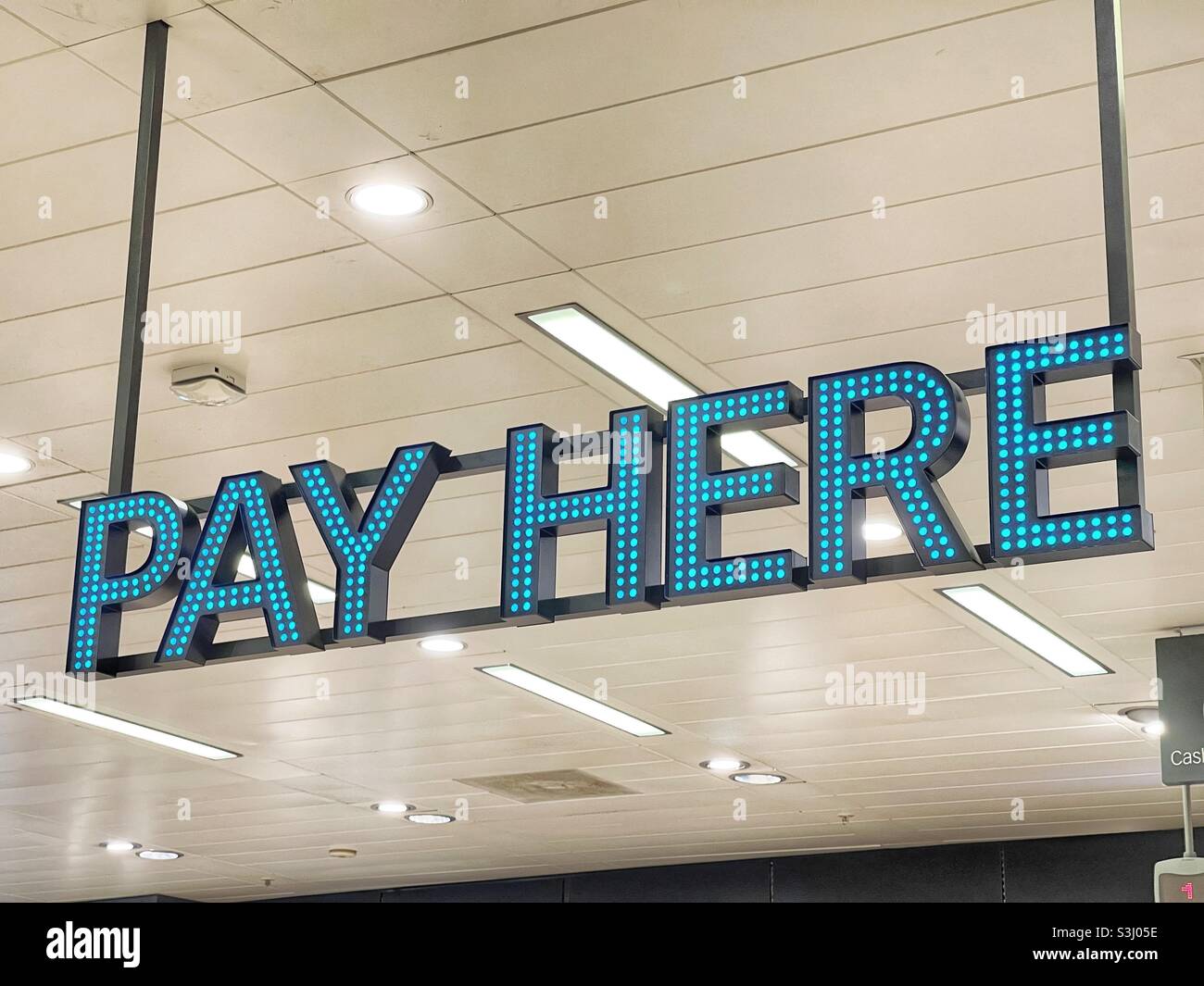 Illuminated Pay Here sign in a store showing shoppers where to pay for their goods Stock Photo