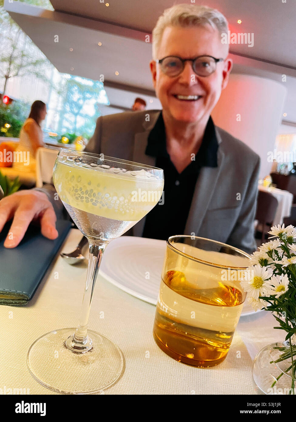 Senior man enjoying a martini at an upscale New York City restaurant 2021, USA - Smartphone Captured Stock Image