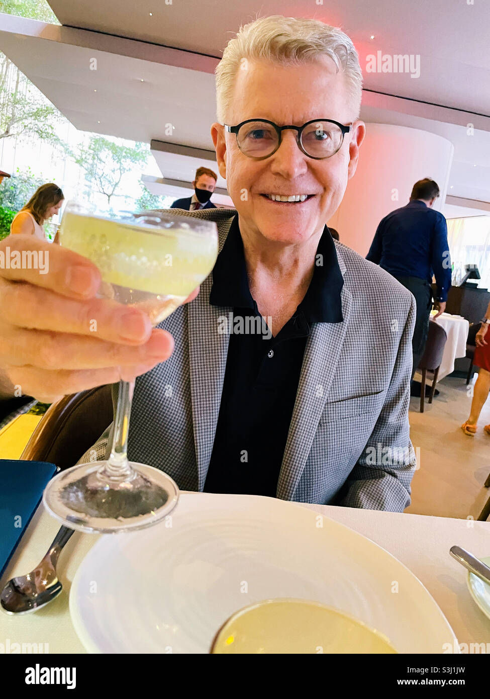 Handsome senior man toasting his dining partner with a martini in an upscale New York City restaurant, 2001, NYC, USA - Smartphone Captured Stock Image