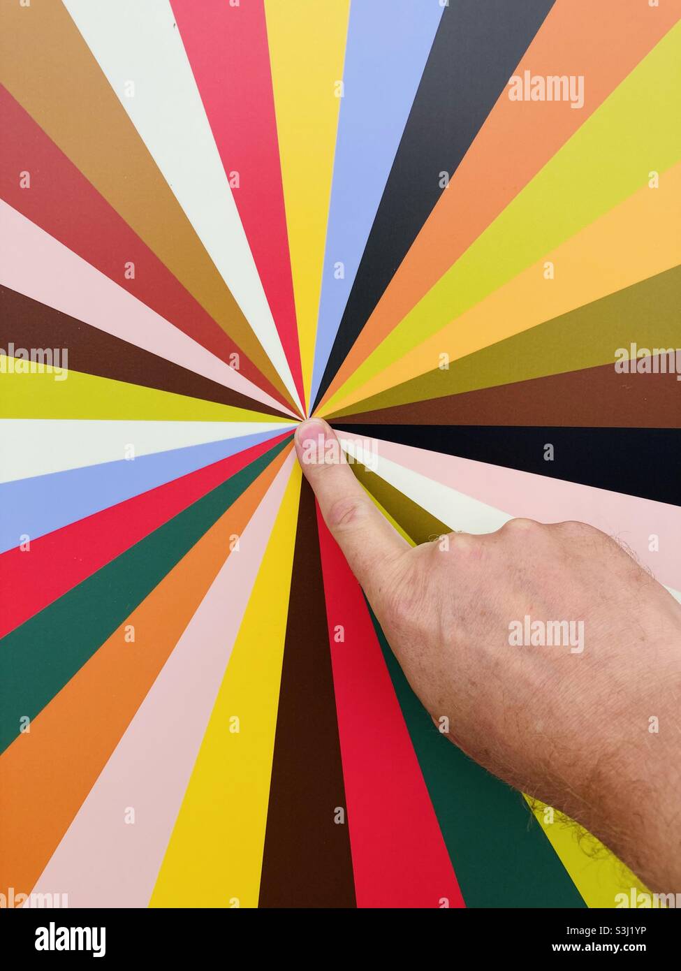 An index finger points to the center of a panel with color rays - Smartphone Captured Stock Image