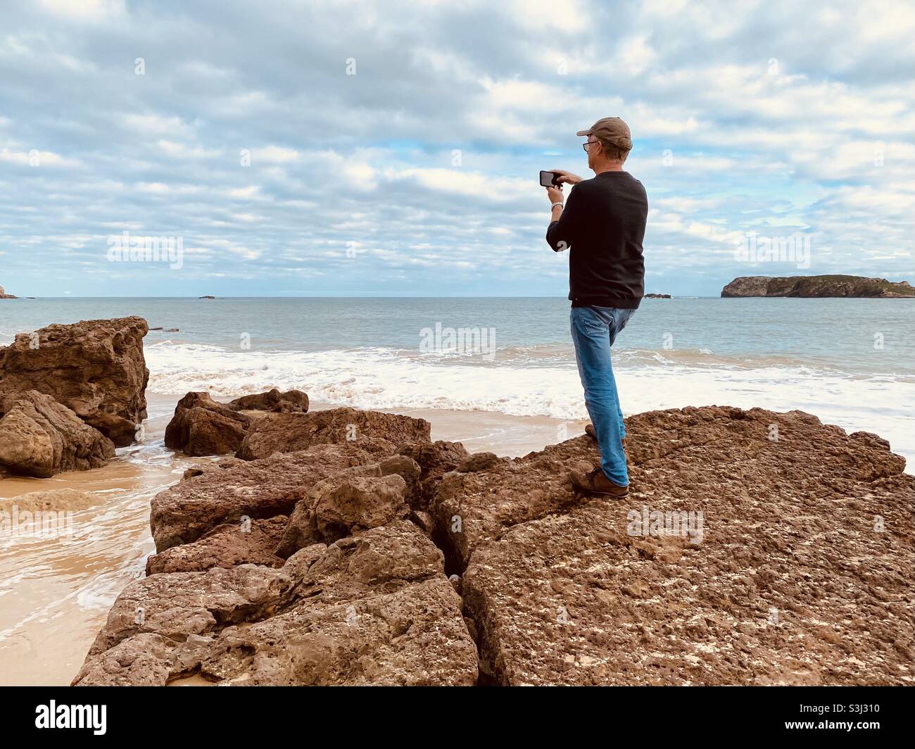 Man taking a photo of the coastline on his phone - Smartphone Captured Stock Image