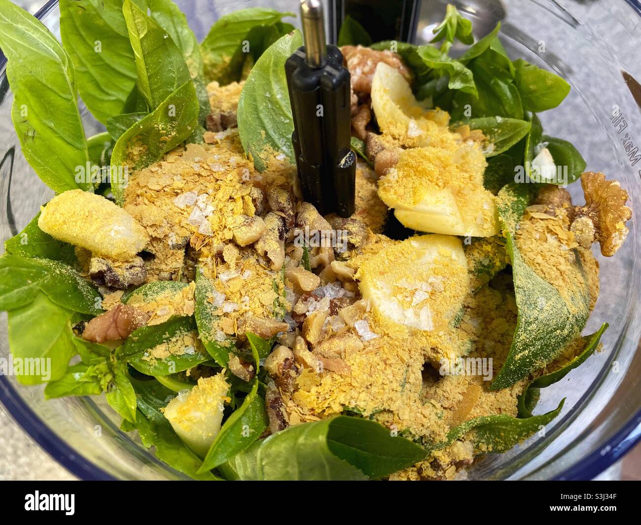 Ingredients for vegan pesto inside a food processor. Stock Photo