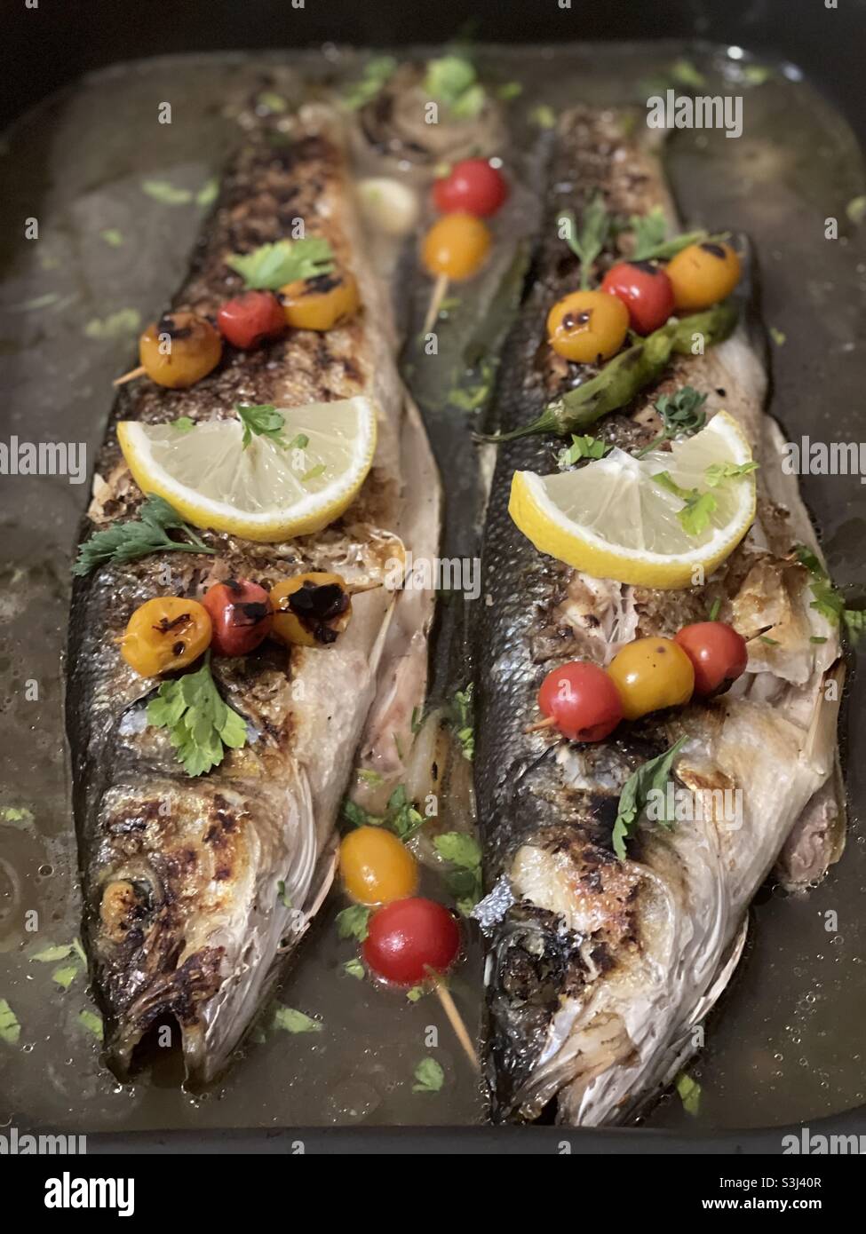 Sea bass in brine, baked in the oven and ready to eat Stock Photo Alamy