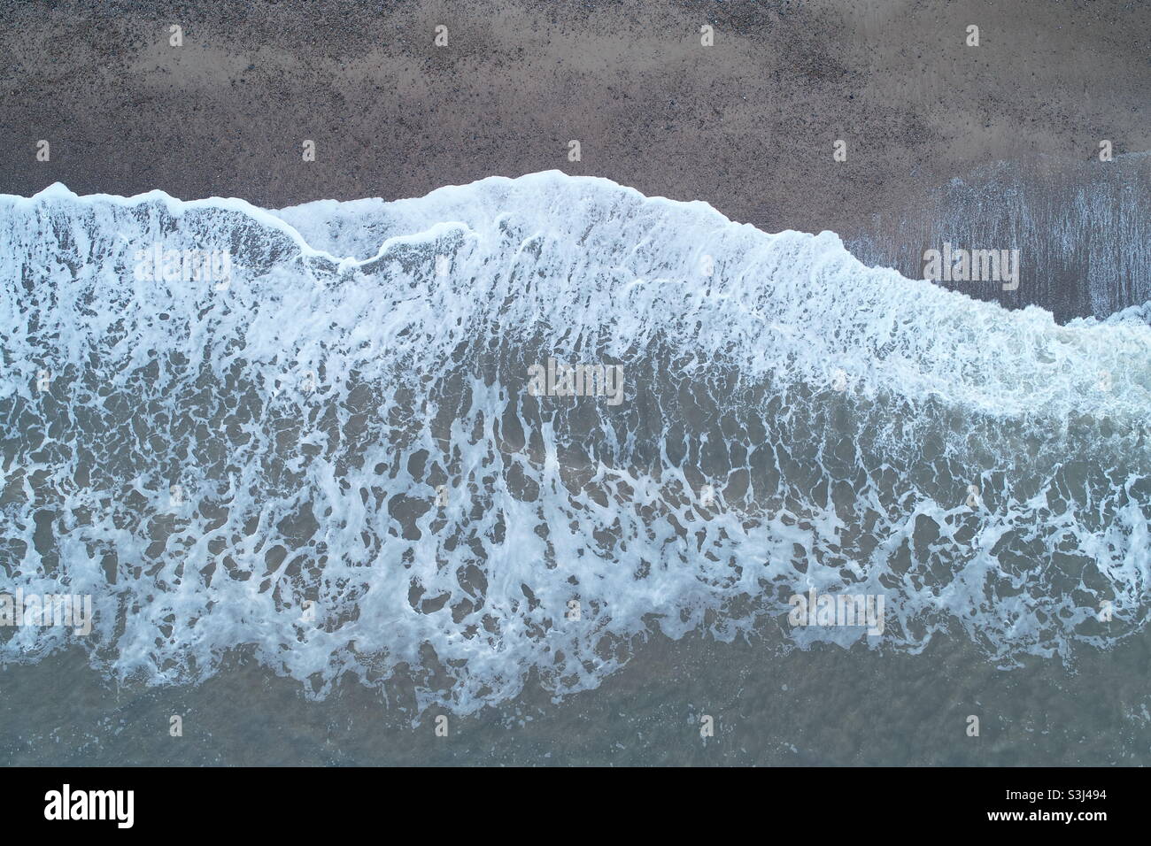 Vertical drone shot of waves breaking on a beach in Suffolk - Smartphone Captured Stock Image