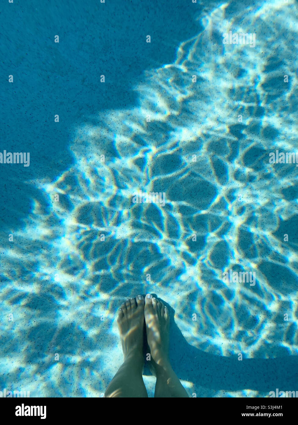 Feet standing in swimming pool Stock Photo